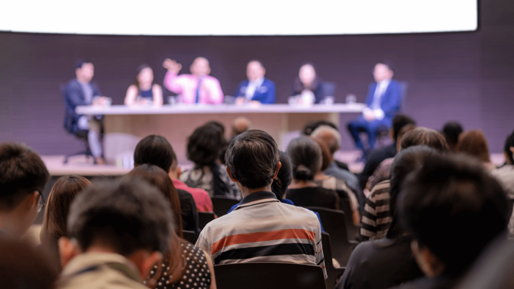 People attending a legal conference event watching a panel of attorneys speak